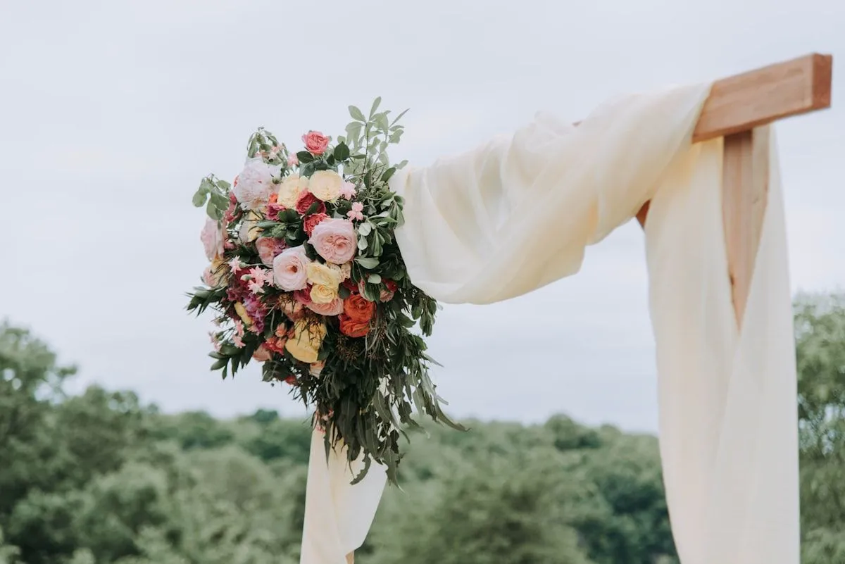Wedding arch with white drapes and a bouquet of pink roses