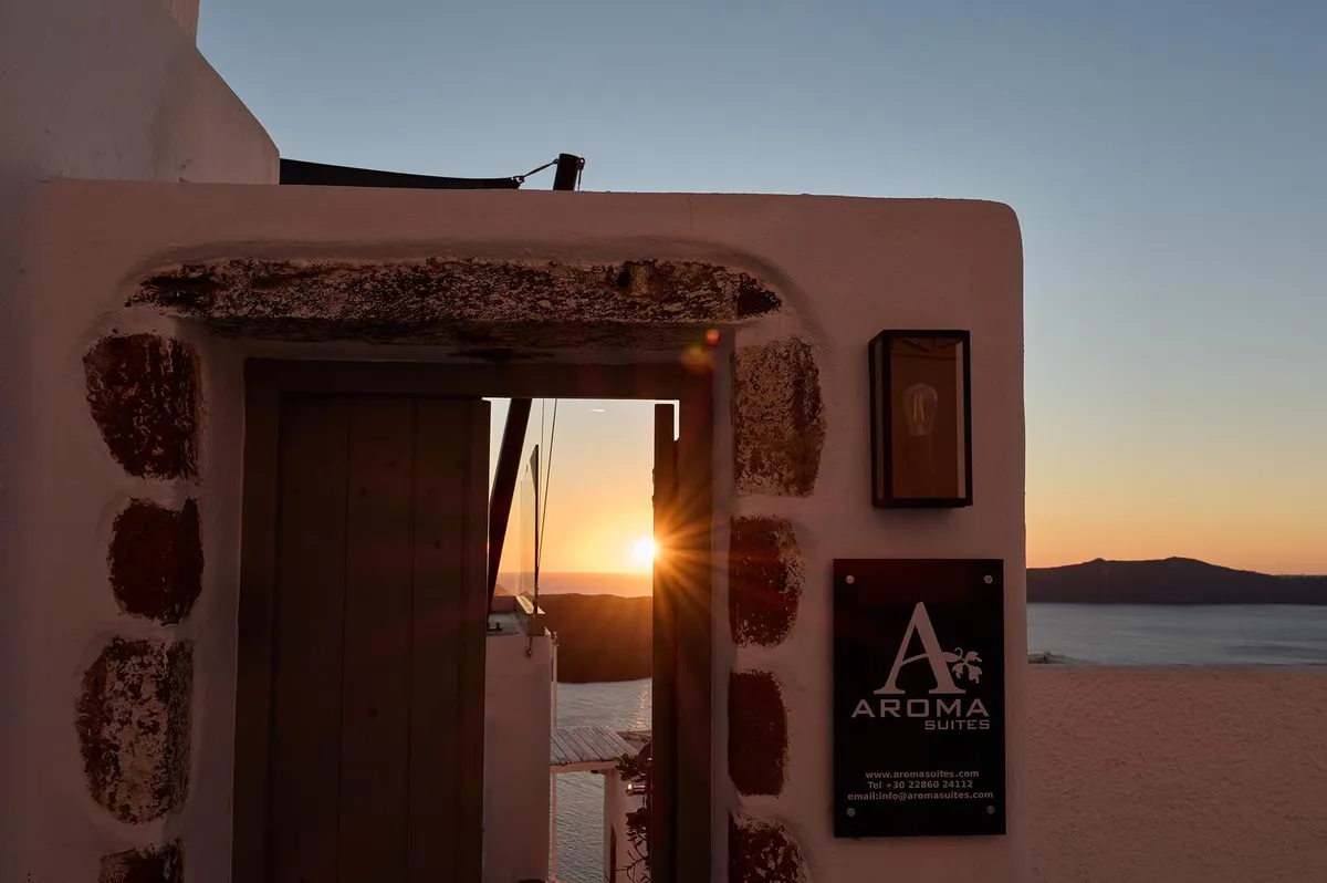 Church dome silhouette against golden Santorini sunset over the caldera