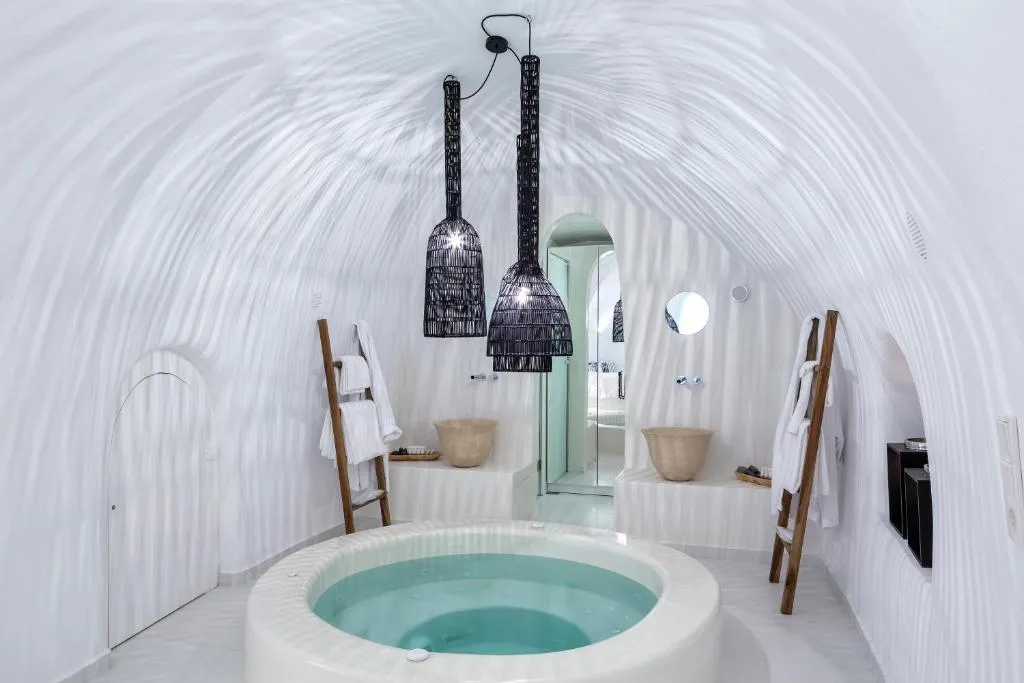Round cave jacuzzi with vaulted white ceiling and lantern lighting at Aroma Suites honeymoon suite Santorini