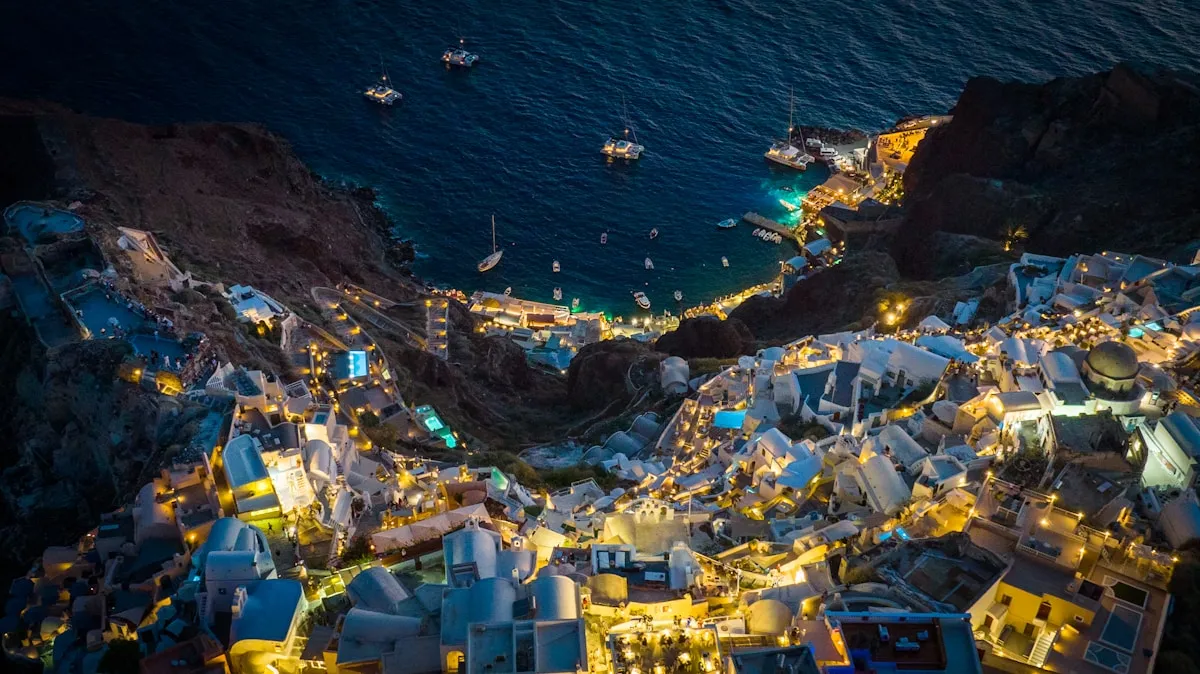 Aerial night view of Santorini with lights glowing along the caldera rim