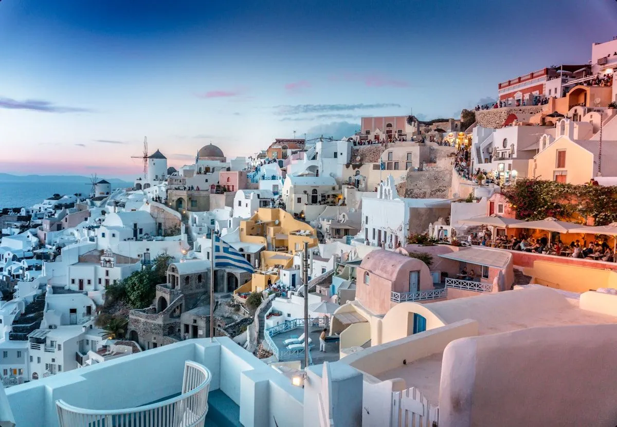 Whitewashed houses stacked on a caldera cliff in Santorini at dusk