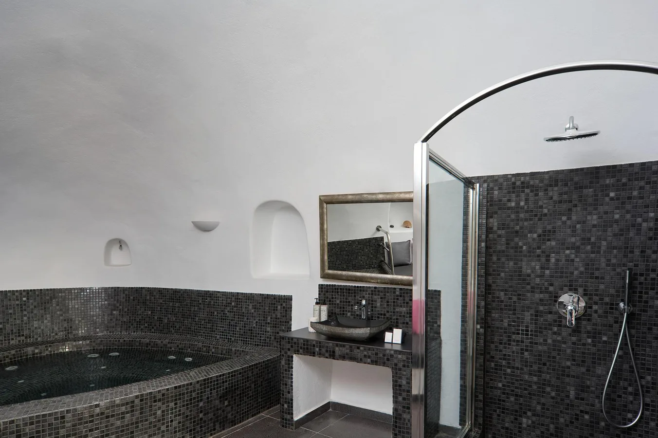 Indoor jacuzzi and rain shower in a cave suite bathroom at Aroma Suites