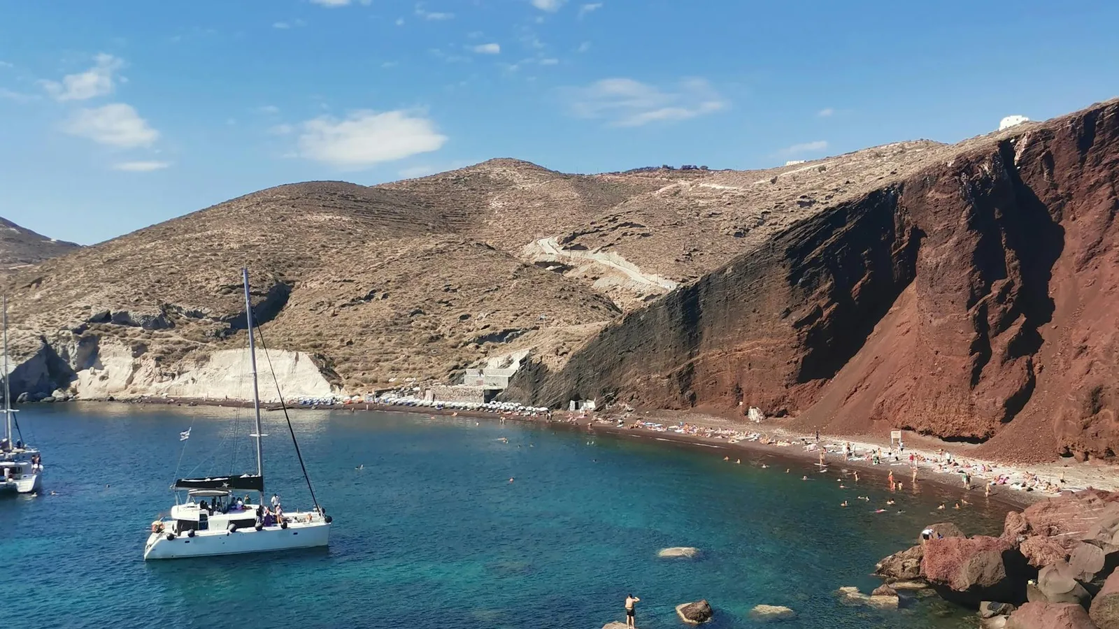 Crystal clear waters and red volcanic cliffs at a Santorini beach